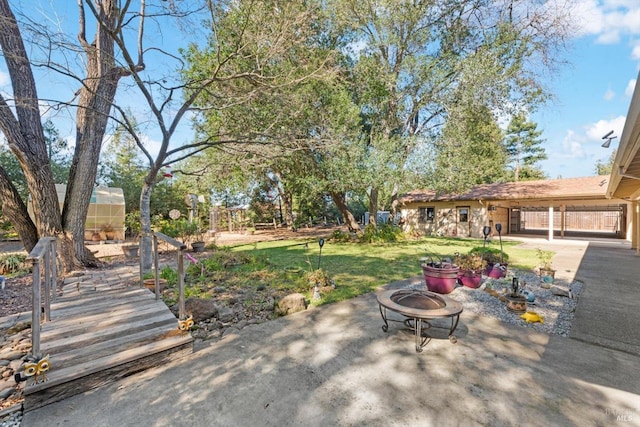 view of yard featuring a fire pit, a patio area, an outbuilding, and an exterior structure