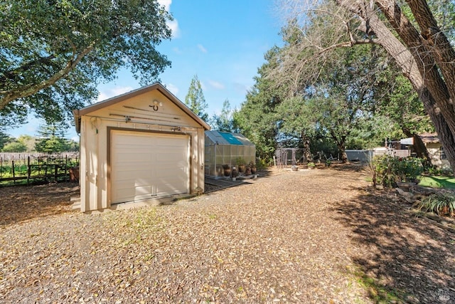 detached garage featuring fence and driveway