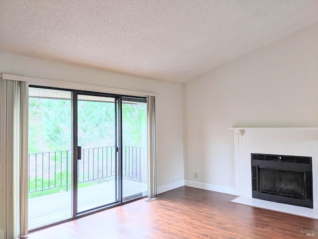 unfurnished living room with a textured ceiling, a fireplace, wood finished floors, and baseboards