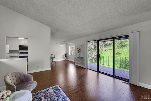 living room featuring dark wood finished floors, a textured ceiling, visible vents, lofted ceiling, and baseboards