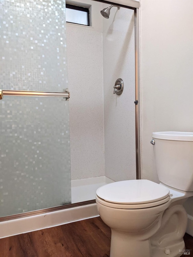 bathroom with a stall shower, toilet, and wood finished floors