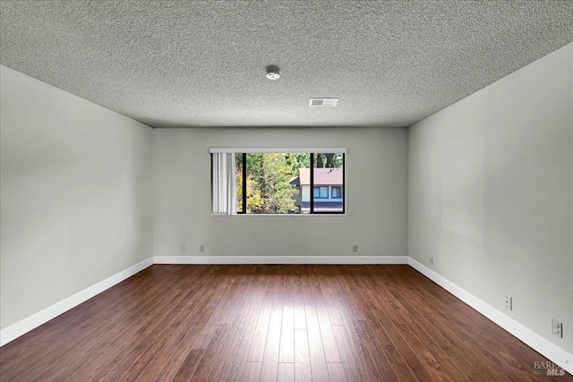 empty room with baseboards, a textured ceiling, wood-type flooring, and visible vents