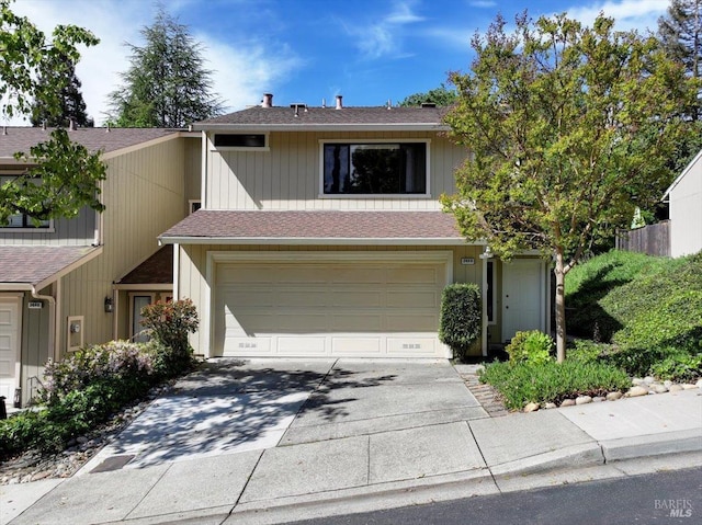 view of front of home with an attached garage, roof with shingles, and driveway