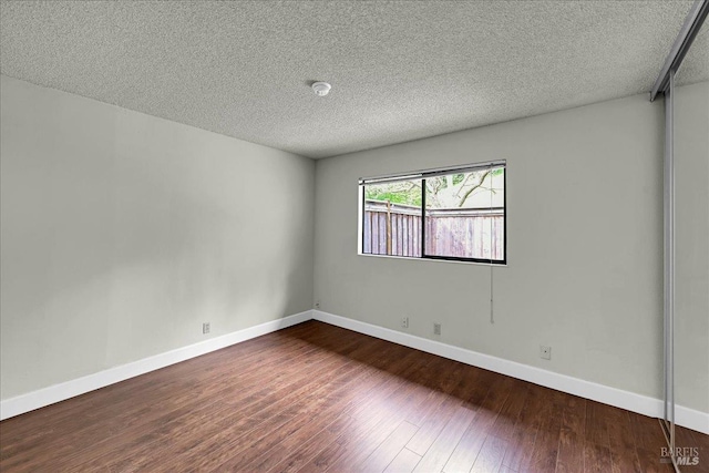 empty room featuring baseboards, wood finished floors, and a textured ceiling