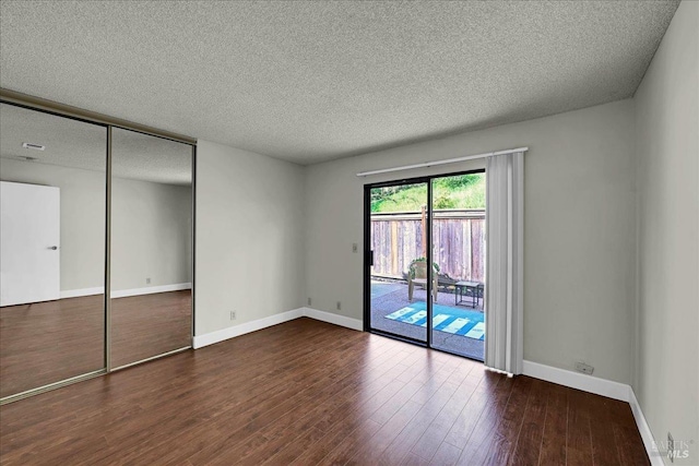 unfurnished bedroom with a textured ceiling, a closet, access to exterior, wood finished floors, and baseboards