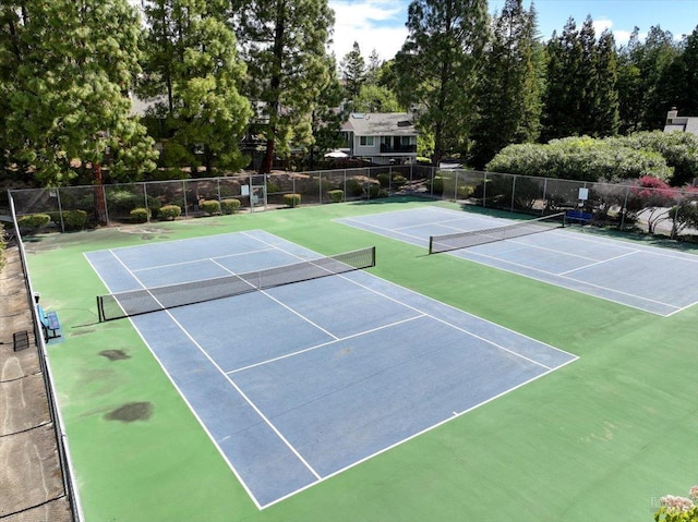 view of tennis court featuring community basketball court and fence