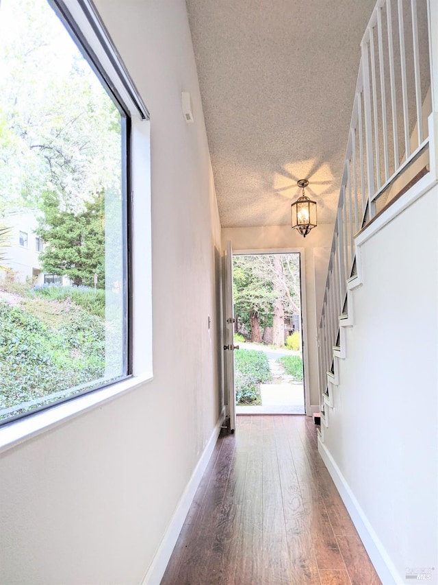 doorway to outside featuring wood finished floors, a textured ceiling, baseboards, and stairs