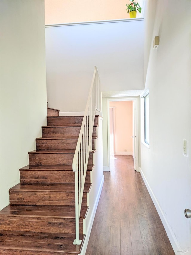 staircase featuring baseboards and hardwood / wood-style flooring