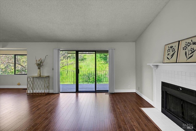unfurnished living room featuring a tiled fireplace, baseboards, and a textured ceiling