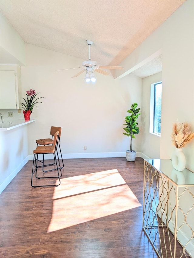 living area with ceiling fan, a textured ceiling, baseboards, and wood finished floors