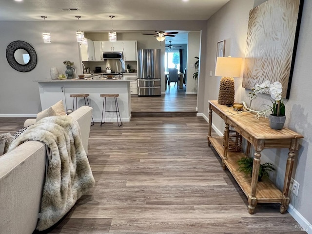 kitchen with a peninsula, a breakfast bar, visible vents, white cabinetry, and appliances with stainless steel finishes