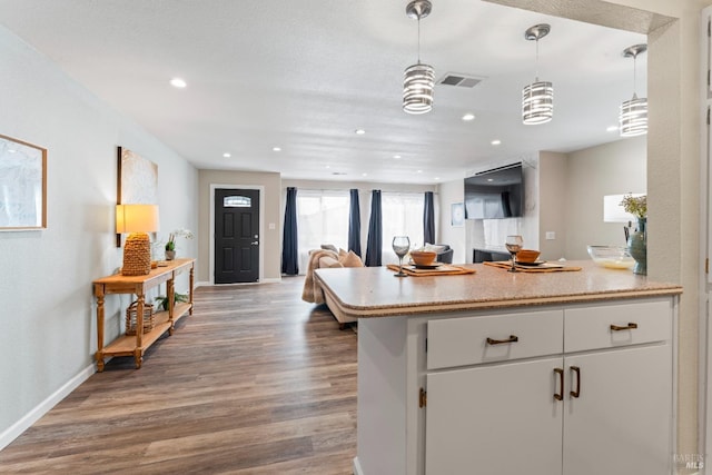 kitchen with light countertops, visible vents, open floor plan, white cabinetry, and wood finished floors