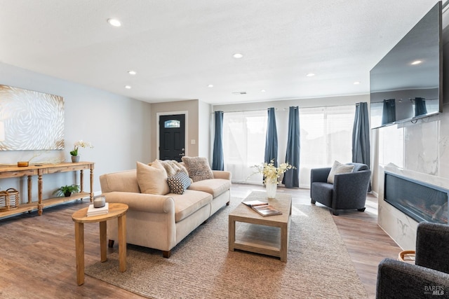 living area featuring a premium fireplace, recessed lighting, visible vents, and light wood-style floors