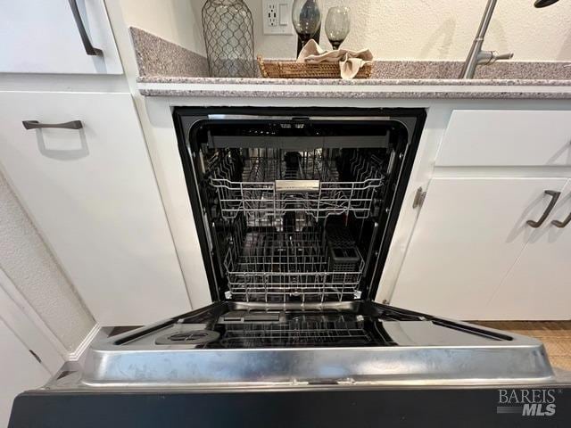 interior details featuring dishwashing machine, a sink, and white cabinetry