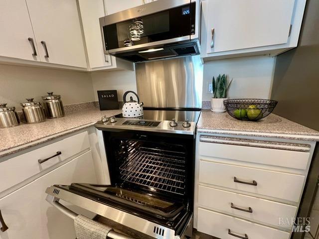 kitchen with light countertops, white cabinets, and stainless steel microwave