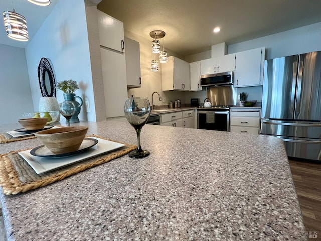 kitchen featuring recessed lighting, stainless steel appliances, white cabinets, light countertops, and decorative light fixtures