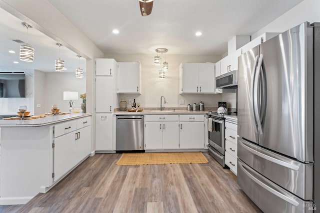 kitchen with white cabinets, appliances with stainless steel finishes, light countertops, and pendant lighting