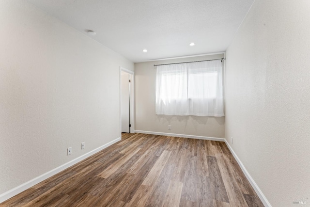 spare room with recessed lighting, wood finished floors, and baseboards