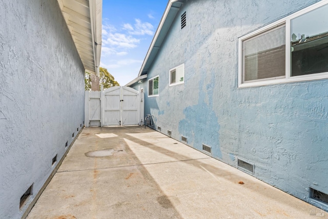 view of property exterior featuring a patio, stucco siding, a gate, crawl space, and fence