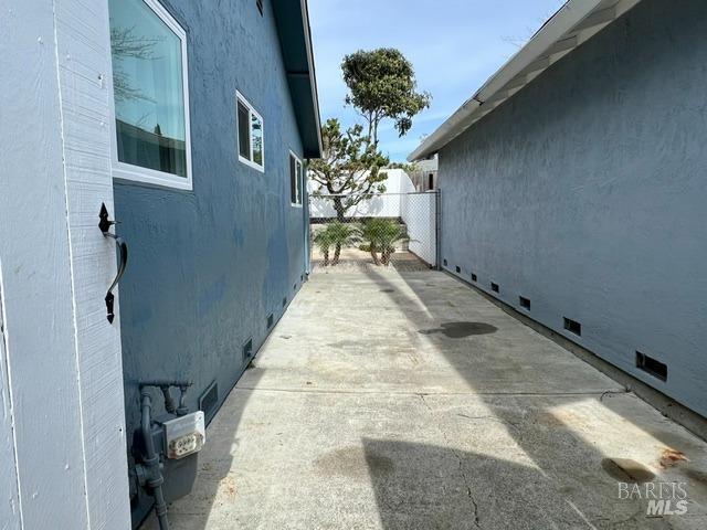 view of side of home featuring crawl space, fence, a patio, and stucco siding