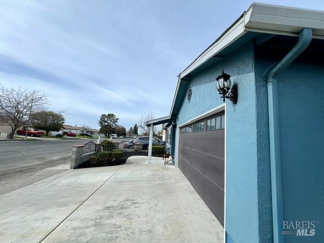 view of side of property featuring a garage, driveway, and stucco siding