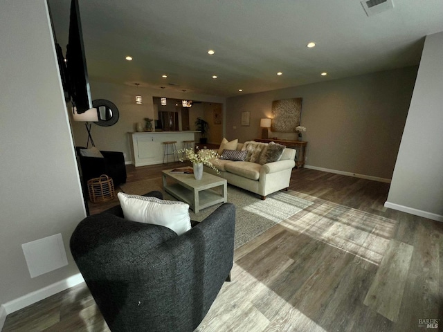 living room with baseboards, visible vents, wood finished floors, and recessed lighting