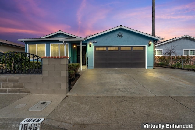 ranch-style home with driveway, an attached garage, fence, and stucco siding