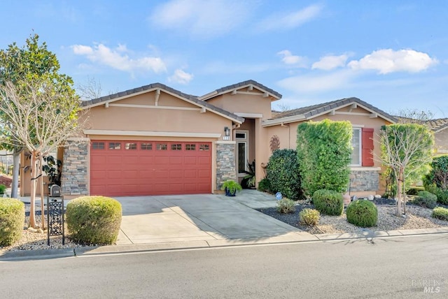 view of front of home featuring an attached garage, driveway, stone siding, and stucco siding