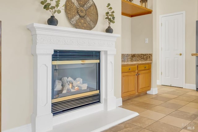 room details with baseboards and a glass covered fireplace