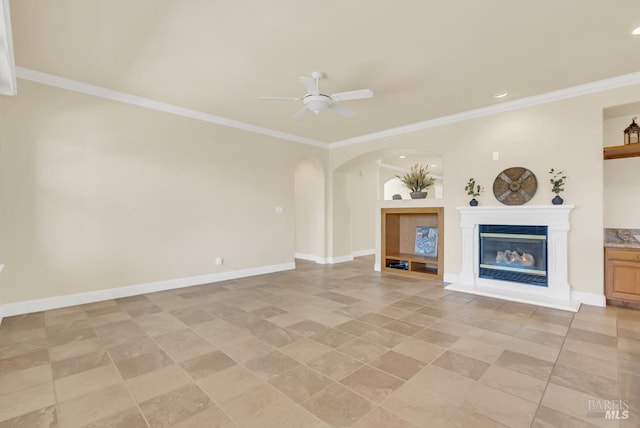 unfurnished living room featuring crown molding, a ceiling fan, arched walkways, and a glass covered fireplace