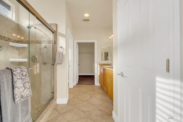bathroom with vanity, baseboards, a stall shower, and visible vents