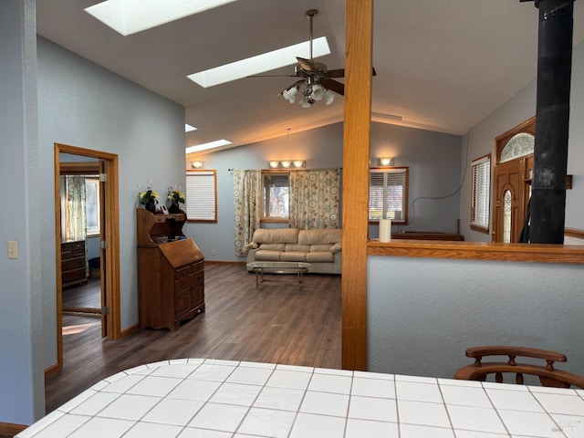 interior space featuring ceiling fan, lofted ceiling with skylight, and wood finished floors