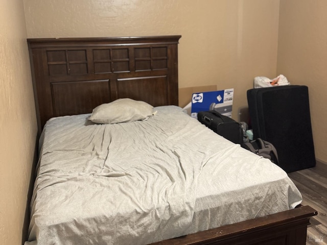 bedroom with wood finished floors and a textured wall