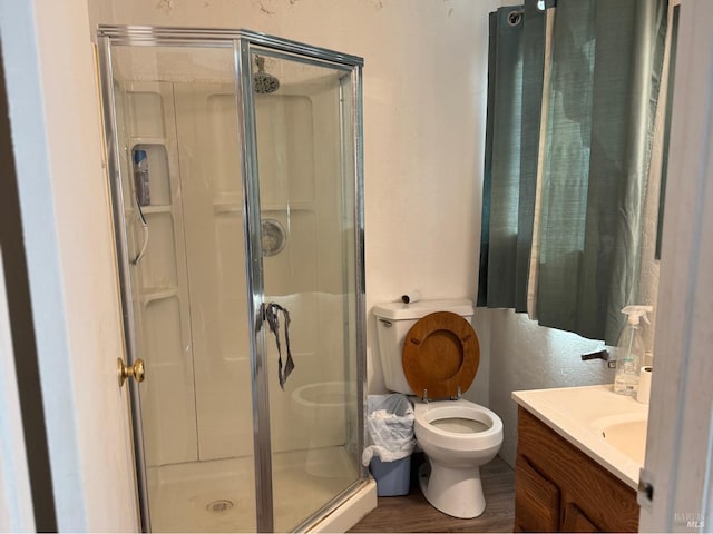 bathroom featuring a stall shower, vanity, toilet, and wood finished floors