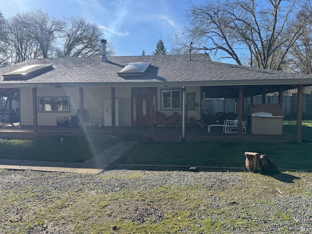 back of property with a yard, a porch, and roof with shingles