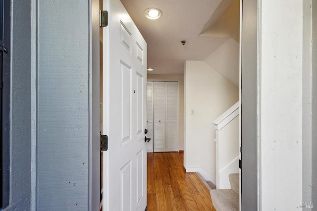 hallway featuring stairs, light wood finished floors, and baseboards