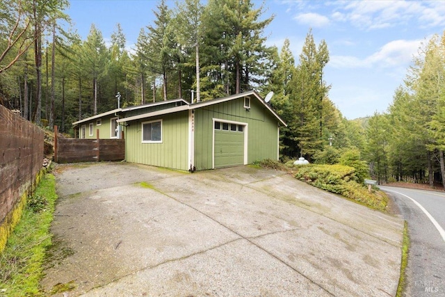 garage featuring concrete driveway and fence