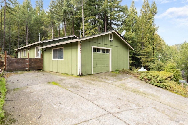 garage with concrete driveway and fence