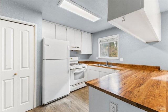 kitchen with under cabinet range hood, white appliances, a sink, white cabinetry, and light wood-style floors