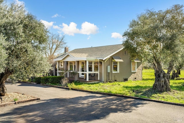 view of front facade featuring covered porch, crawl space, stucco siding, a front lawn, and a chimney