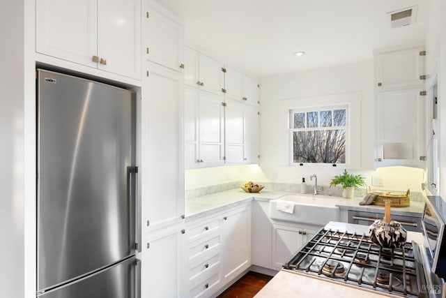 kitchen with stainless steel appliances, light countertops, visible vents, and white cabinetry