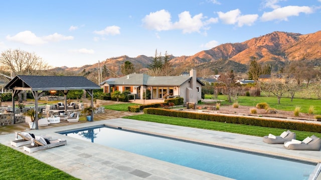 outdoor pool featuring a patio area, a mountain view, a gazebo, and a lawn