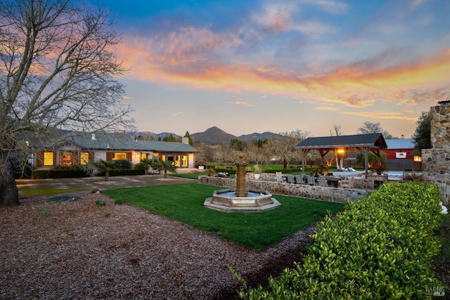 rear view of house featuring driveway, a patio, a gazebo, a yard, and a mountain view