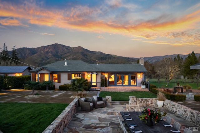 back of house with a patio area, a chimney, a mountain view, and a yard