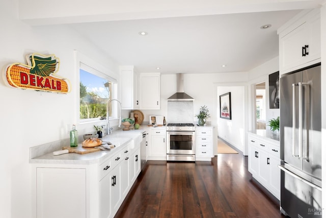 kitchen with stainless steel appliances, wall chimney exhaust hood, light countertops, and white cabinetry