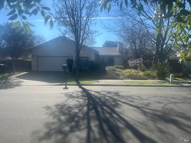 ranch-style house with stucco siding, concrete driveway, an attached garage, fence, and a tiled roof