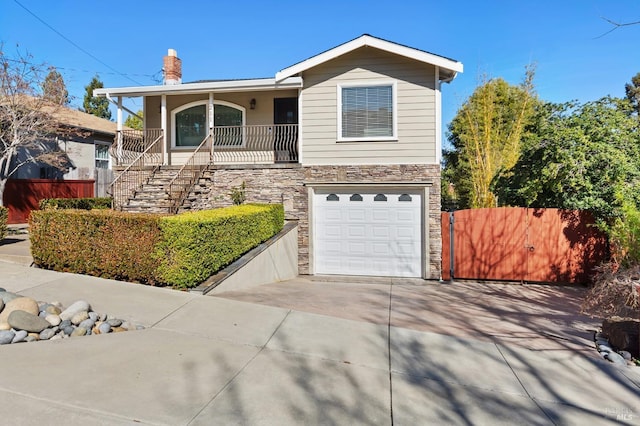 view of front facade featuring concrete driveway, stone siding, an attached garage, stairs, and fence