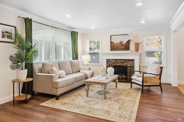 sitting room with ornamental molding, wood finished floors, and a stone fireplace