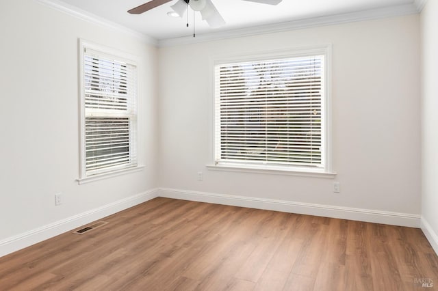 unfurnished room featuring ornamental molding, a healthy amount of sunlight, visible vents, and wood finished floors