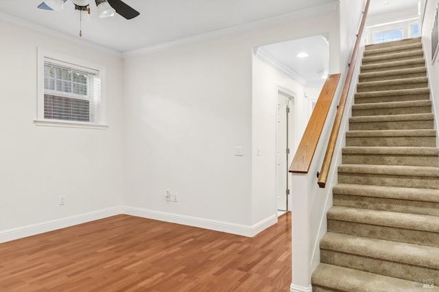 stairs with ceiling fan, ornamental molding, wood finished floors, and baseboards